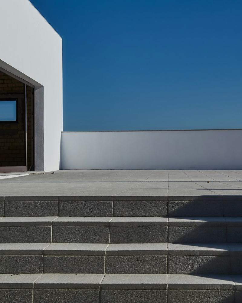 Dark charcoal stone steps in strong sunlight against a white wall