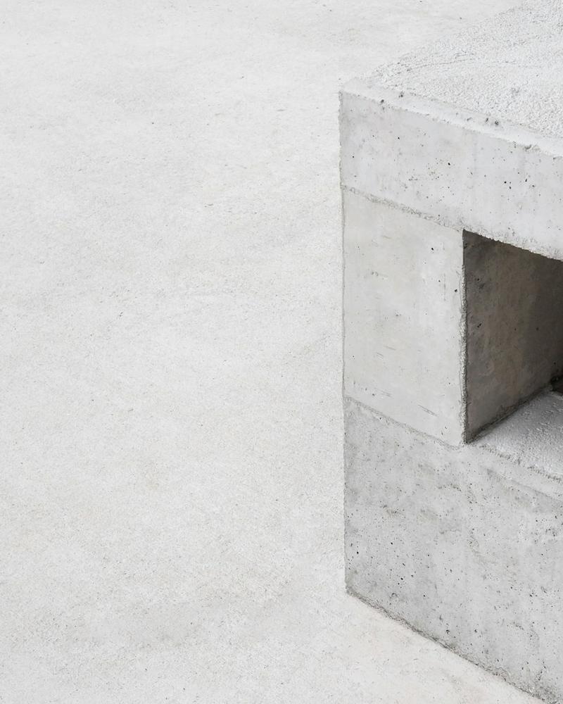 Smooth pale concrete-like surface beside a cast block with a square opening