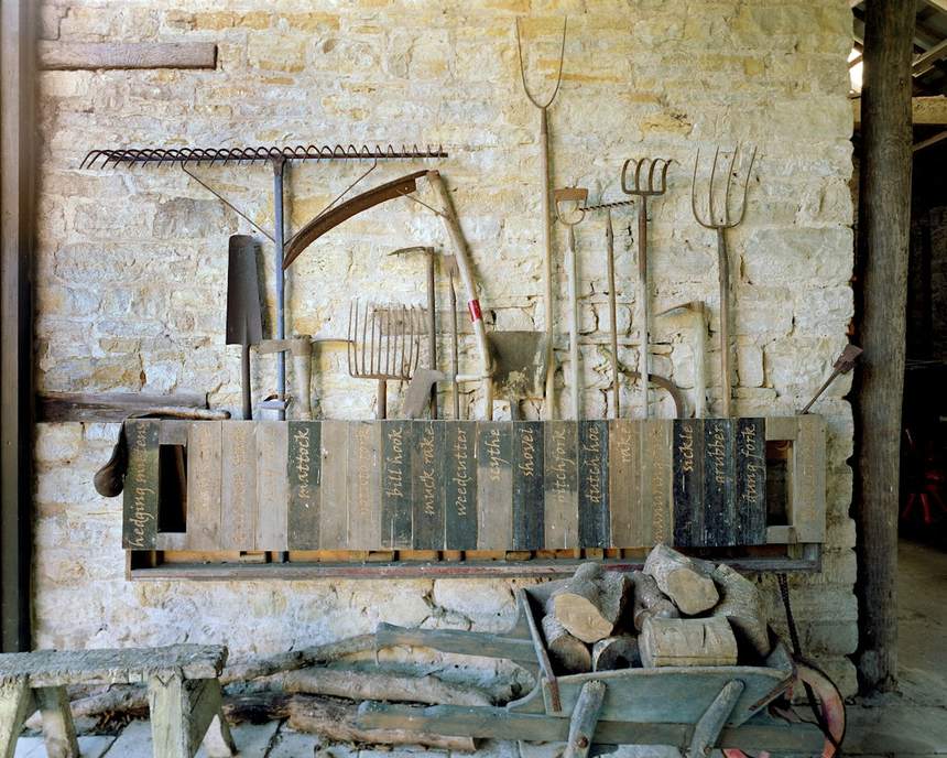 Old hand tools hanging on a limestone wall in a barn