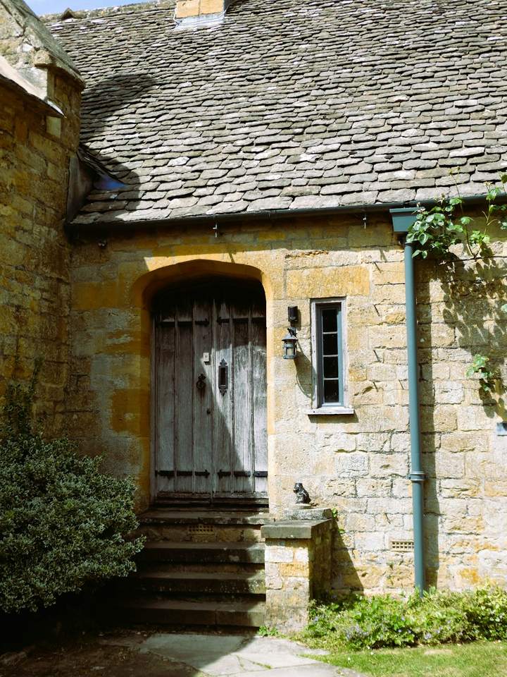 Weathered oak door in a Cotswold stone wall, reached by worn stone steps