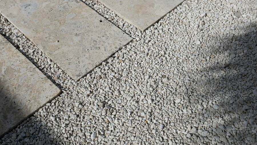 Close view of pale stone slabs set into fine gravel, in soft shade