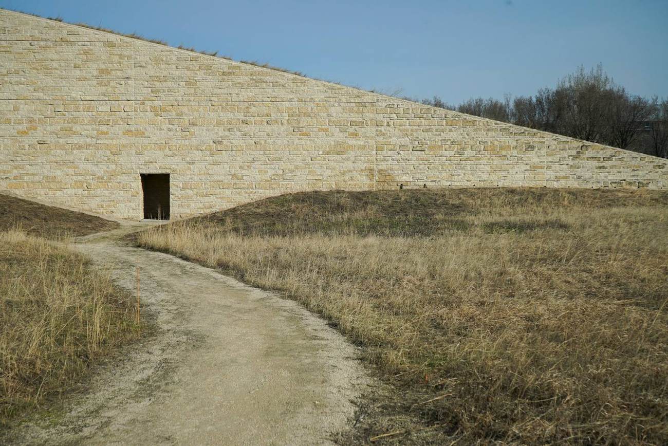 A long sandstone wall rising out of dry grassland, with a single dark doorway